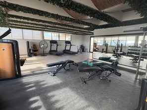 Ein Fitnessstudio mit Laufbändern, Kraftgeräten und einem Spiegel, der die Geräte reflektiert.