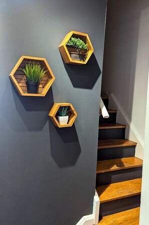 Eine Treppe mit Holzbeschlägen und drei sechseckige Pflanzgefäße aus Holz mit Pflanzen an einer grauen Wand.