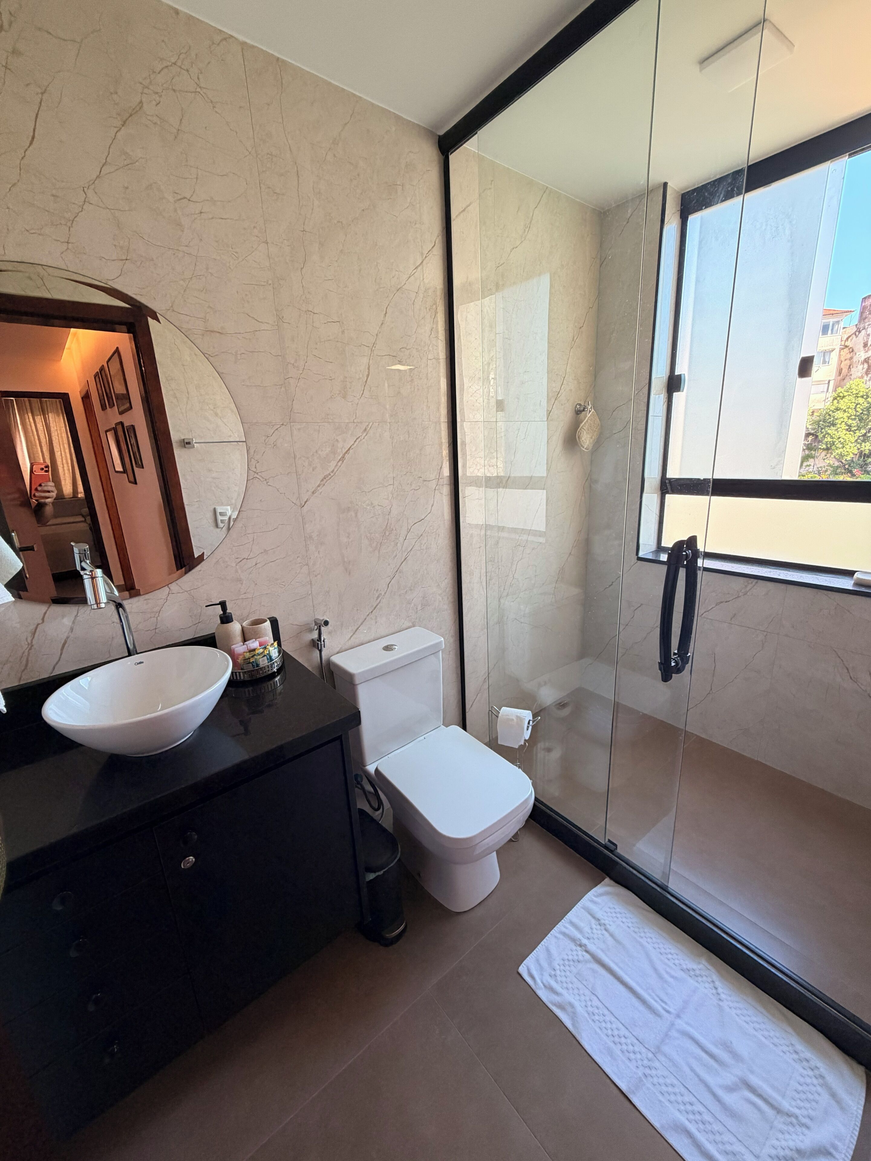 Un baño moderno con cabina de ducha de vidrio, lavamanos blanco y retrete.