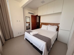 Ein Hotelzimmer mit einem Bett, einem Kleiderschrank, einem Spiegel und einer Klimaanlage.