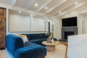 A modern living room with a sectional sofa, a round coffee table, and a fireplace. - Luxury Wellness Retreat with Cedar Sauna, Cold Plunge, Gym and Outdoor Oasis (Los Angeles)