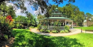 A gazebo with a roof, surrounded by lush greenery and trees.