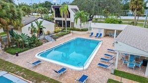 A rectangular pool with lounge chairs and a covered seating area.