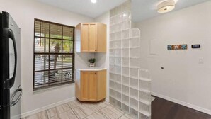 Une pièce avec une fenêtre, une armoire, un sol carrelé et un luminaire fixé au mur.