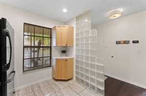 A room with a window, a cabinet, a tiled floor, and a wall-mounted light fixture.
