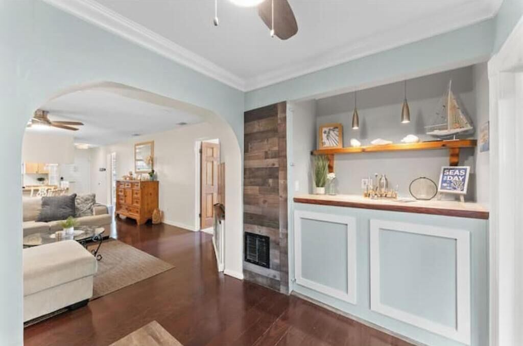 A modern living room with a fireplace, a kitchen area with a wooden countertop, and a dining area with a table and chairs.