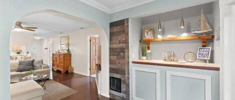A modern living room with a fireplace, a kitchen area with a wooden countertop, and a dining area with a table and chairs.