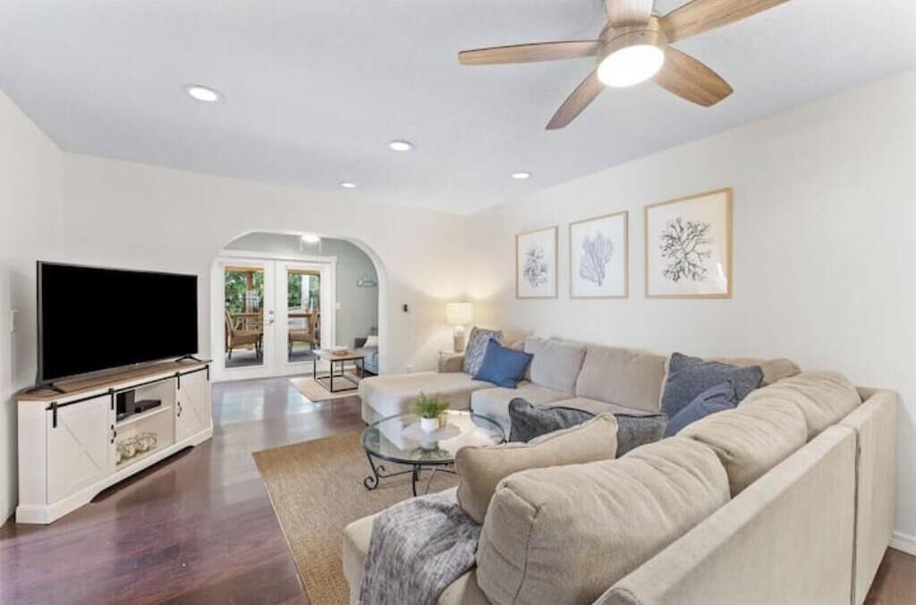 A living room with a flat-screen TV, a ceiling fan, and a sofa.