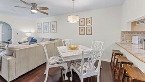 Un coin repas avec une table blanche, des chaises et un ventilateur de plafond.