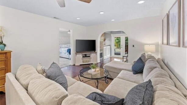 A modern living room with a sofa, a coffee table, and a ceiling fan.