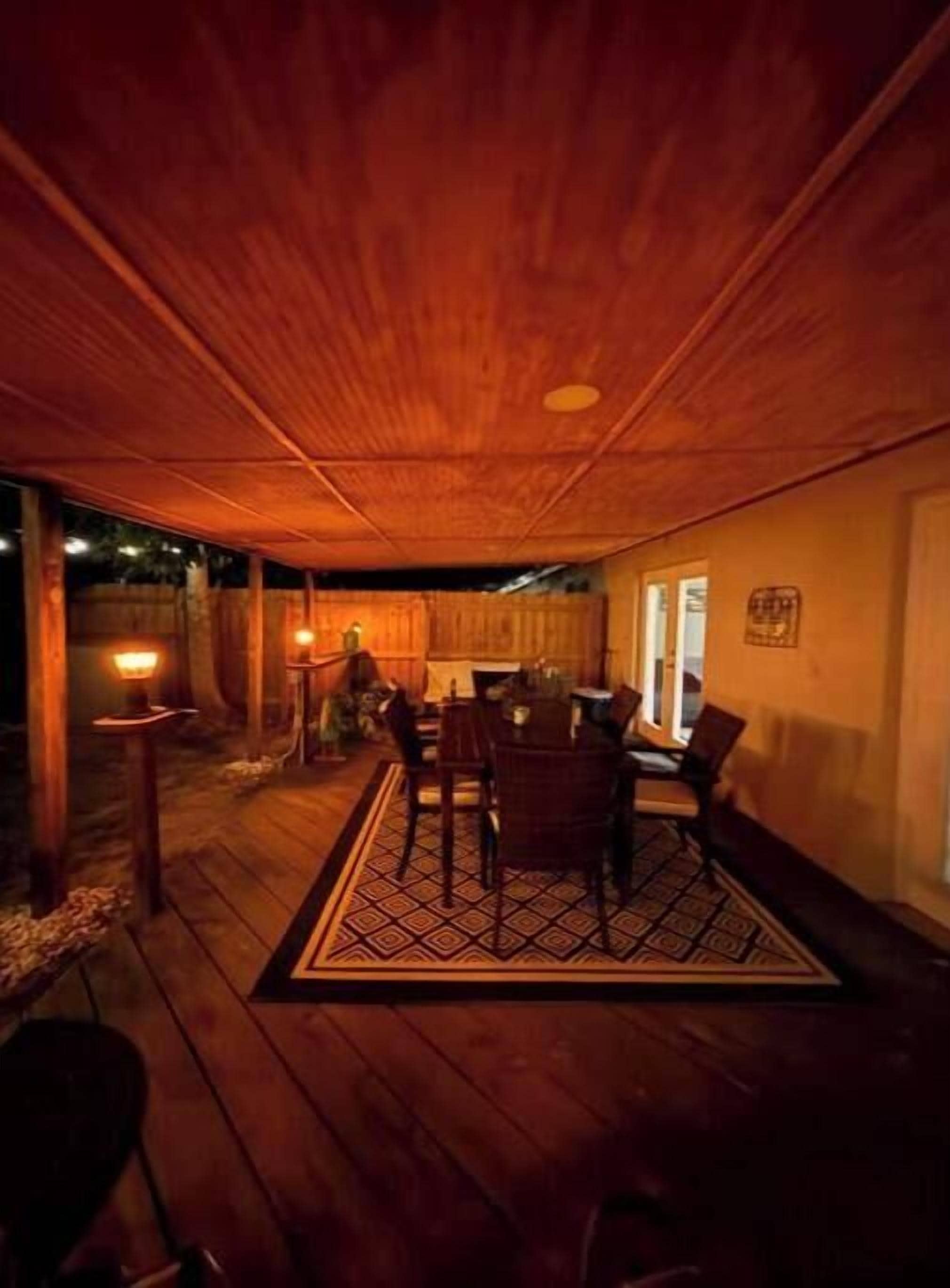 Una habitación con piso de madera, una mesa de comedor y sillas, un tapete y una obra de arte colgada en la pared.