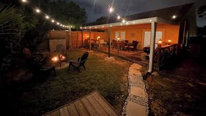An outdoor patio area with string lights, a fire pit, and a covered seating area.