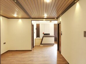 Un pasillo con piso de madera que conduce a una recepción con mostrador y una planta pequeña.