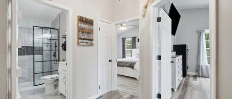 A spacious hallway with a modern bathroom, a bedroom, and a living area.