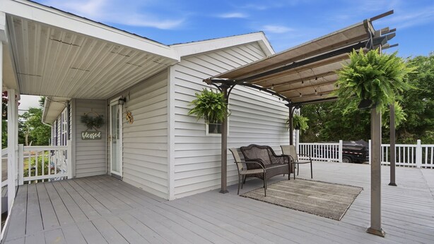 A covered porch with a bench and potted plants.