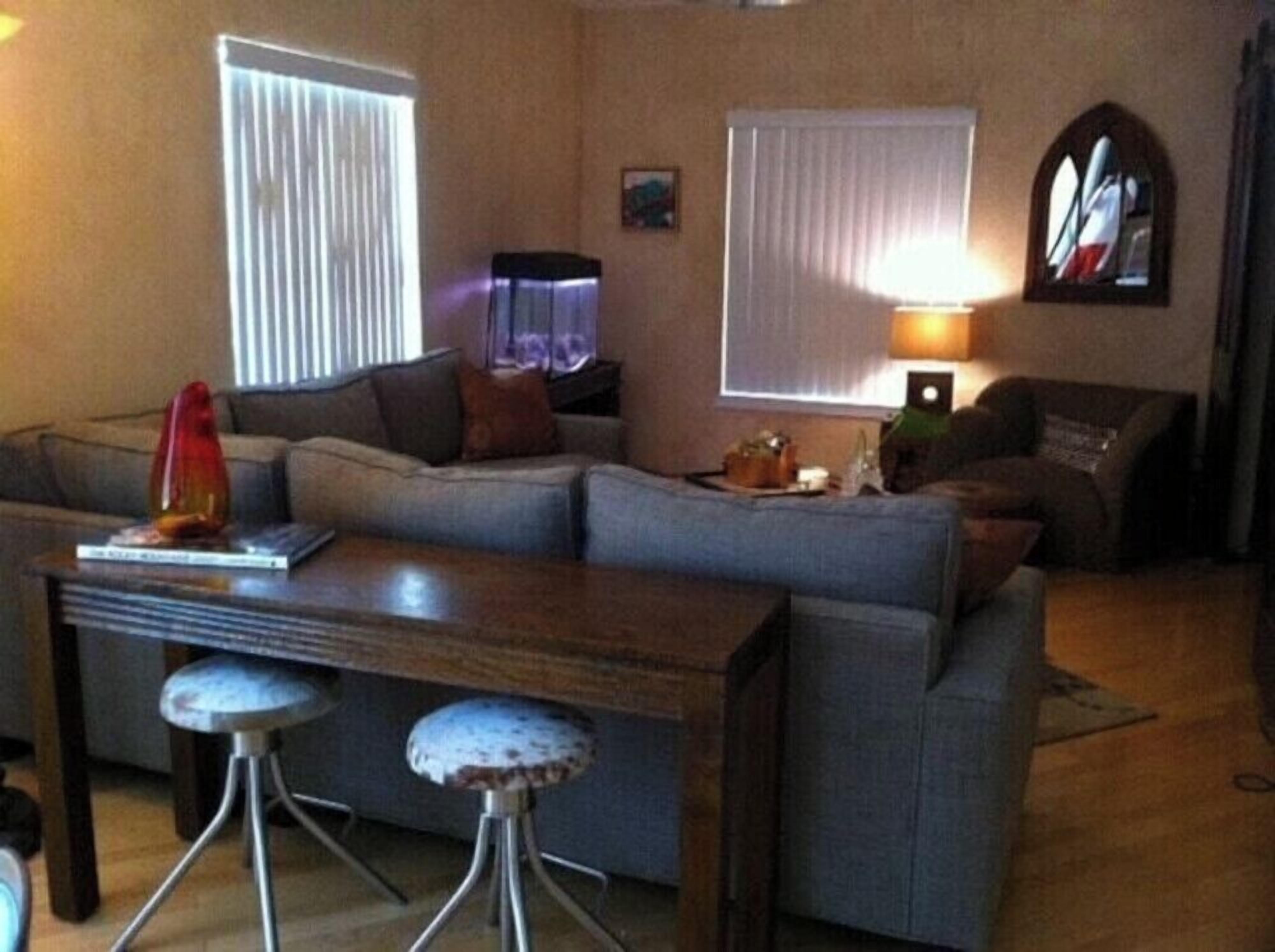 A living room with a sofa, a coffee table, and a bar stool.