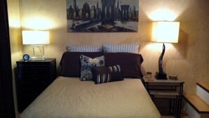 Een hotelkamer met een groot bed, twee nachtkastjes, een lamp en een schilderij aan de muur.