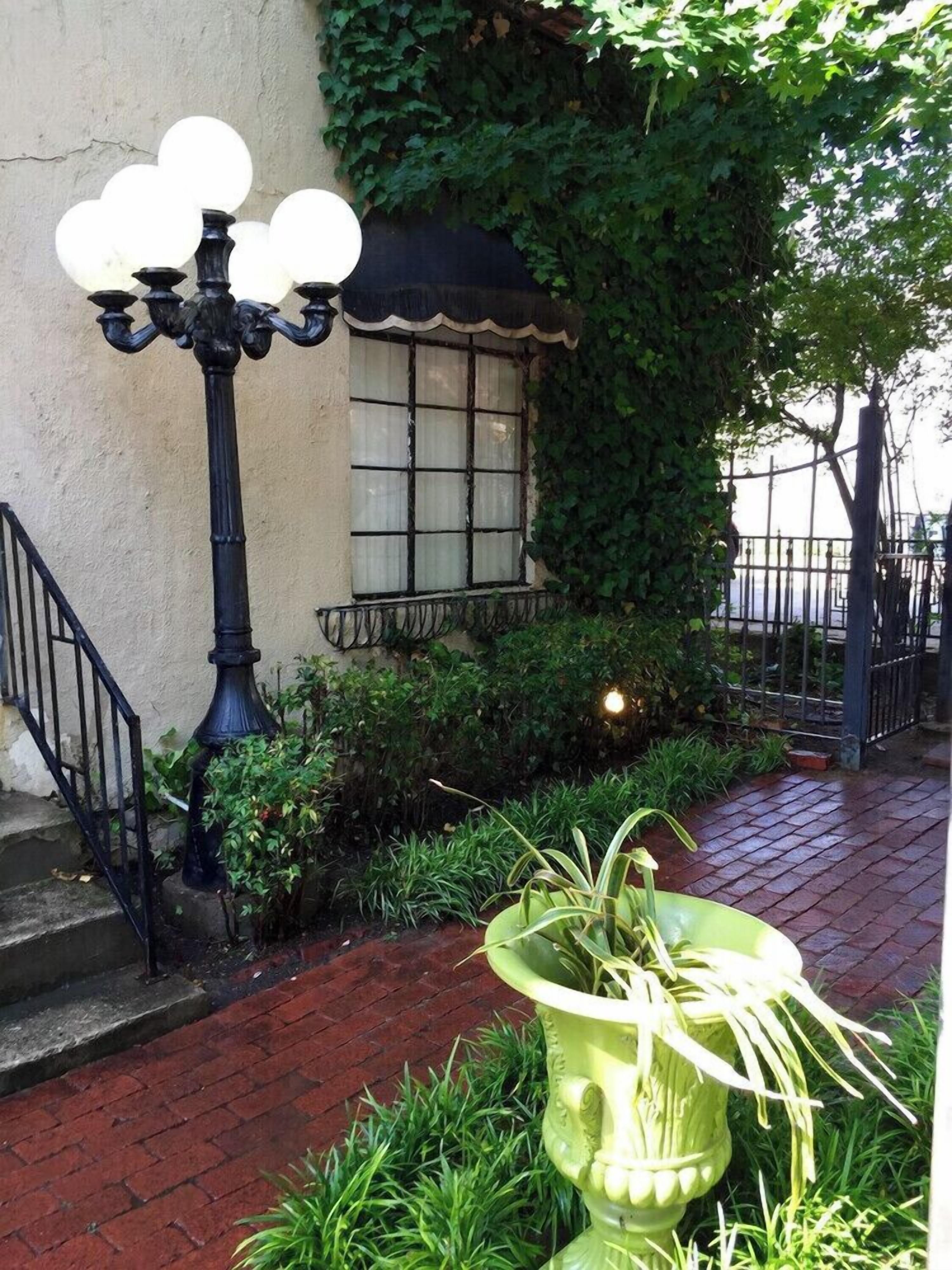 A street lamp, a window with a curtain, and a planter with plants.