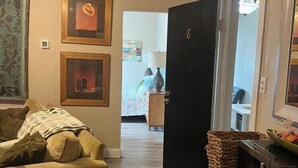 A living room with a sofa, a green side table, and a door leading to another room. - Comfortable 1BR Condo in Downtown (Fort Worth)