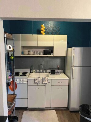 Eine kleine Küche mit Herd, Spüle und Kühlschrank.