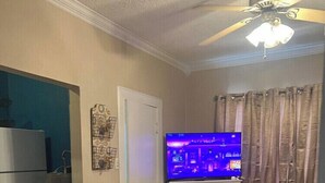 A living room with a sofa, a television, a fireplace, and a ceiling fan. - Comfortable 1BR Condo in Downtown (Fort Worth)