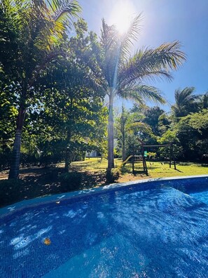 A swimming pool surrounded by lush greenery and a clear blue sky.