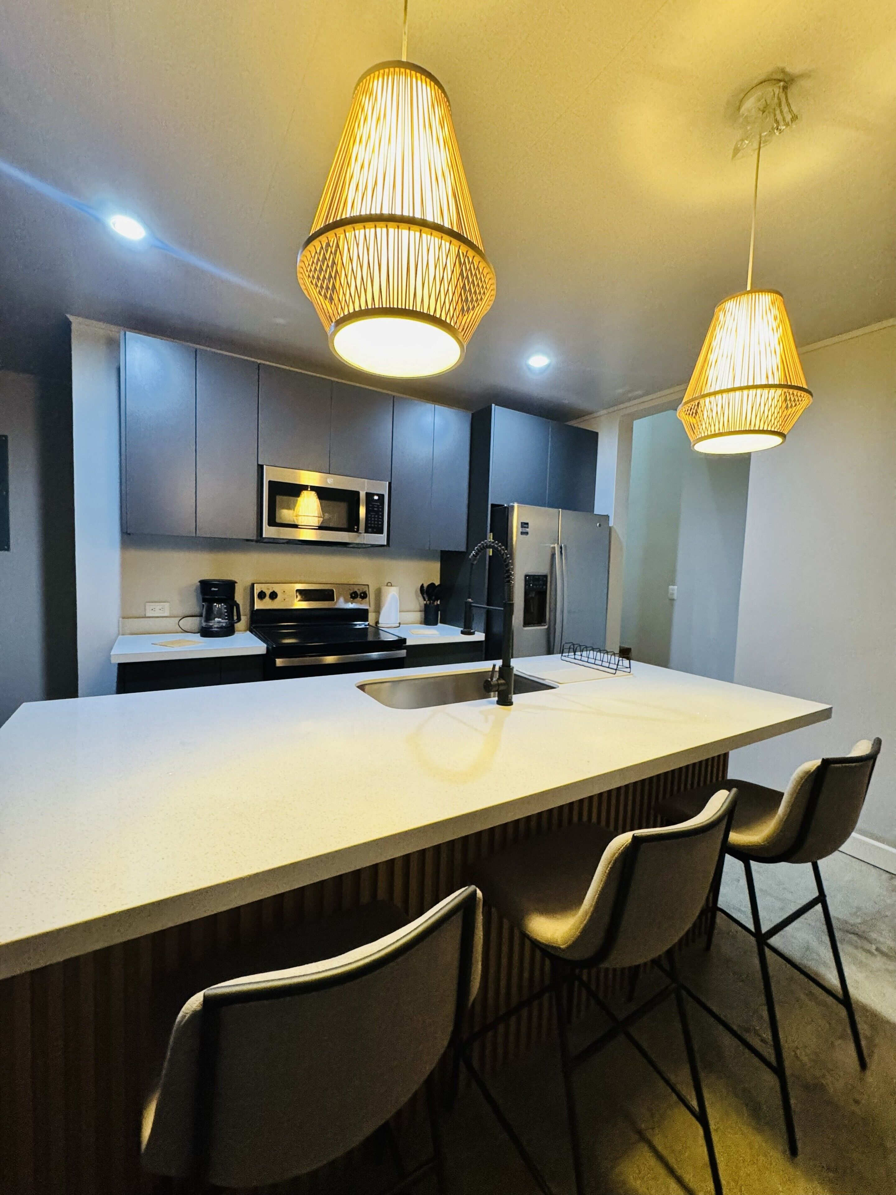 A modern kitchen with a central island, stainless steel appliances, and pendant lighting.