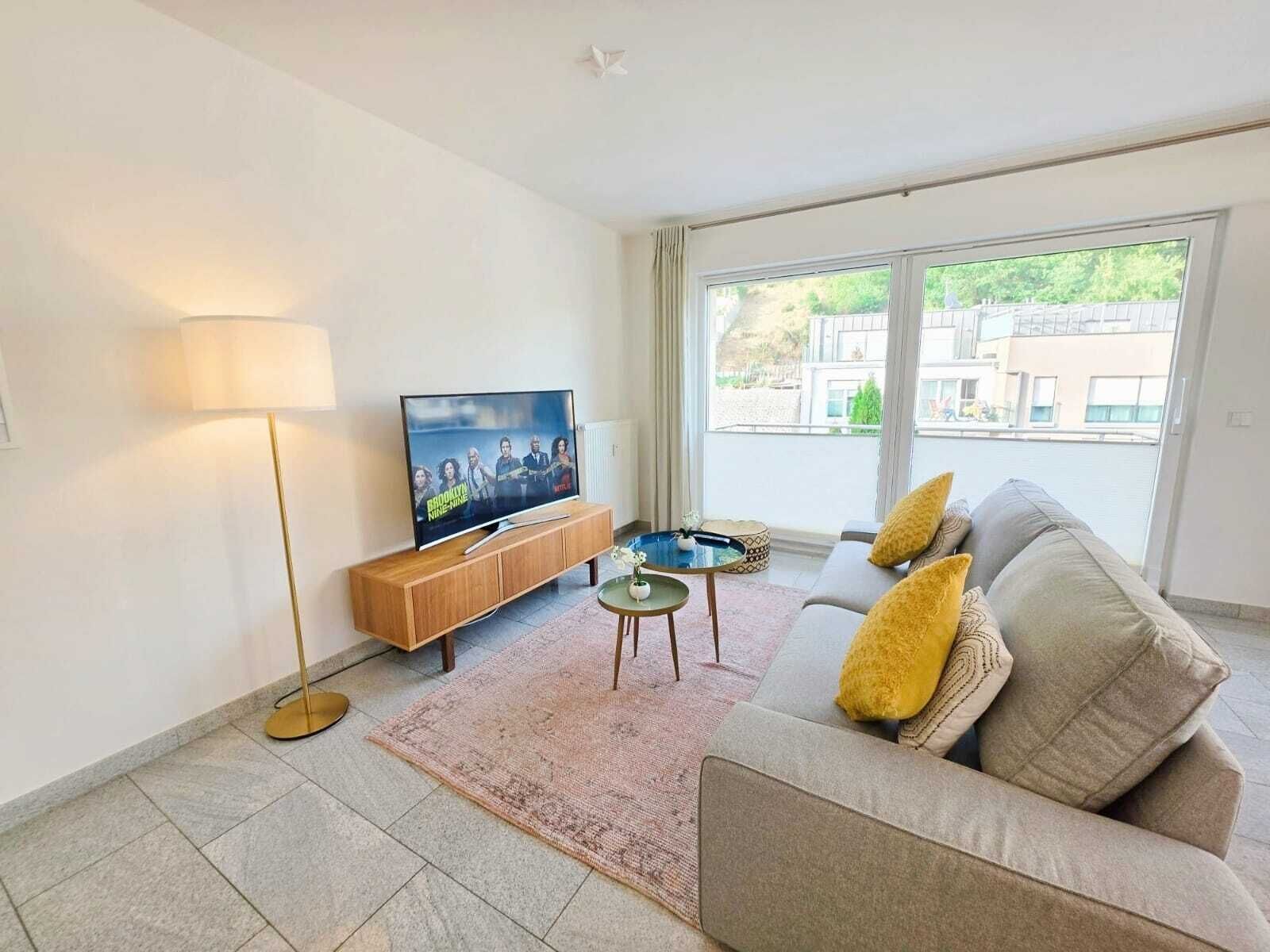 Un salon moderne avec un téléviseur à écran plat, un canapé, une table basse et un lampadaire.