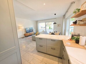 A modern kitchen with a marble countertop, grey cabinets, and a dining area with a table and chairs. - Premium 2BR Apartment w balcony&parking (Luxembourg)