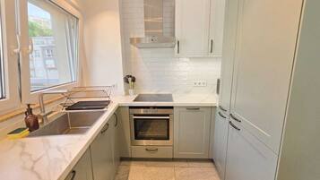 A compact kitchen with a built-in oven, a sink, and a window providing natural light.