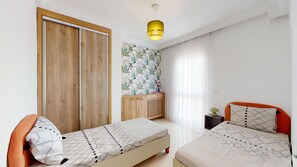 Ein Schlafzimmer mit zwei Betten, einem Kleiderschrank, einer Kommode und einer Deckenleuchte.