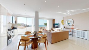 Una cocina moderna con comedor, una sala de estar con sofá y vista al mar.