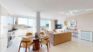 Eine moderne Küche mit Essbereich, ein Wohnbereich mit Sofa und Blick auf das Meer.