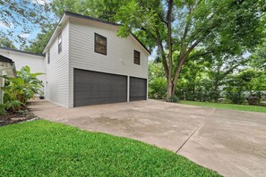 A two-story residential building with a garage, surrounded by a well-maintained lawn and trees. - Lara Retreat- 6B/4.5 BT- Private Pool and Paris- Game room (Houston)