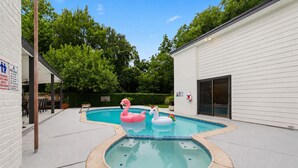 A swimming pool with two inflatable flamingos and a unicorn float, surrounded by a white building and greenery. - Lara Retreat- 6B/4.5 BT- Private Pool and Paris- Game room (Houston)