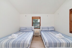 Ein kleines, sauberes Zimmer mit zwei Einzelbetten, einem Fenster und einer Holztür.