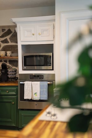 Een keuken met witte kastjes, een magnetron, een oven en een koffiezetapparaat.