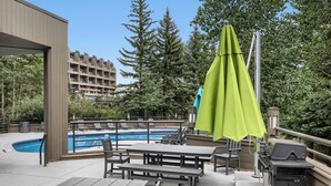 An outdoor pool area with a wooden deck, lounge chairs, and a barbecue grill. - Freshly Updated Ski-In Ski-Out 2BR Beaver Run (Breckenridge)