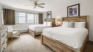 A hotel room with two beds, a desk, a chair, a ceiling fan, and a window with curtains. - Freshly Updated Ski-In Ski-Out 2BR Beaver Run (Breckenridge)