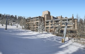 Pista de esquí cubierta de nieve con un edificio de varios pisos al fondo.