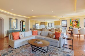 Ein modernes Wohnzimmer mit Ecksofa, Couchtisch und Essbereich mit Stühlen.