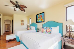 A hotel room with two beds, a ceiling fan, a window, and a painting on the wall. - Condo B305 - 2 Bdrm Luxury Condo with Ocean Views (Cabo San Lucas)