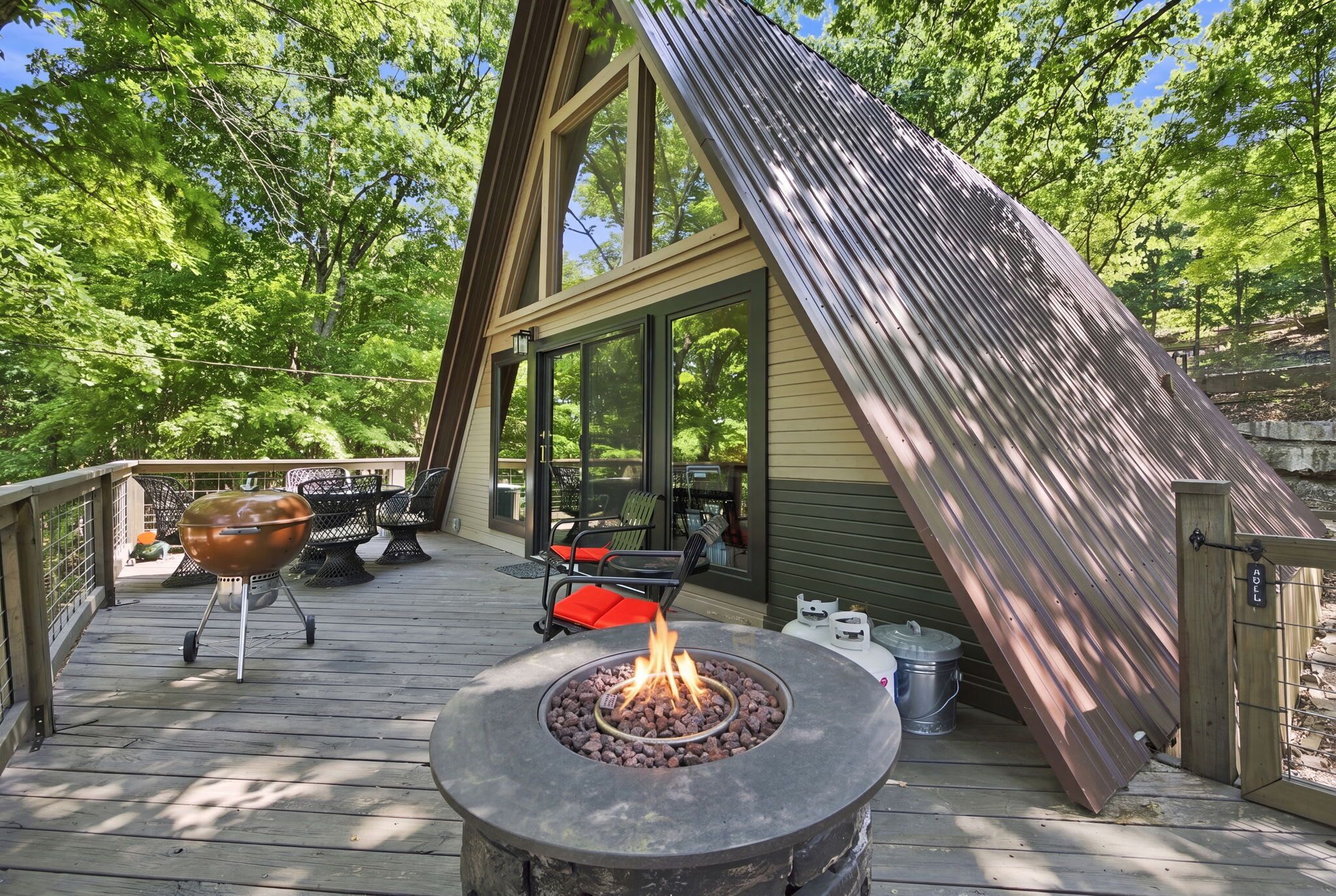 A deck with a fire pit, outdoor seating, and a grill.
