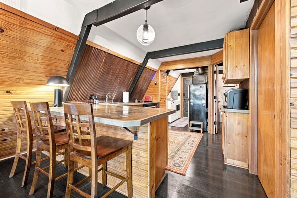 A modern kitchen with a wooden island, bar stools, and a built-in oven.