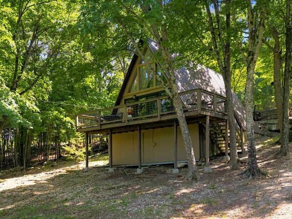 A cabin with a balcony, surrounded by trees.