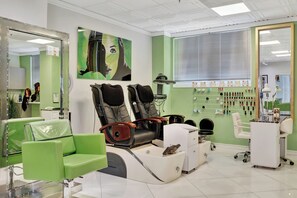 A salon with green walls, multiple seating areas, and a variety of hair styling tools on display. - The Drift On The Ocean (Fort Lauderdale)