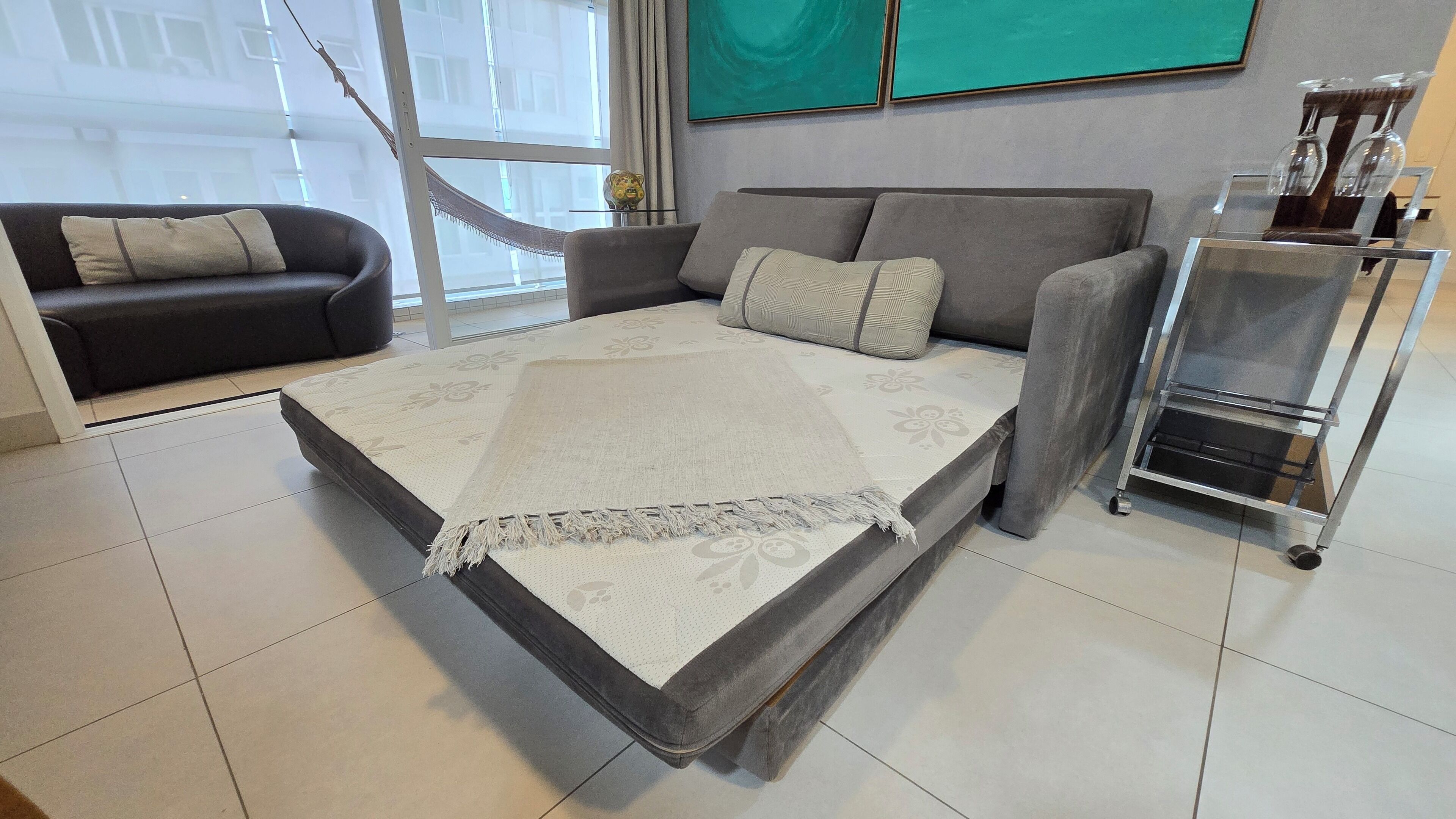 Uma sala de estar moderna com um sofá, uma mesa de centro e um aparador de vidro com objetos decorativos.