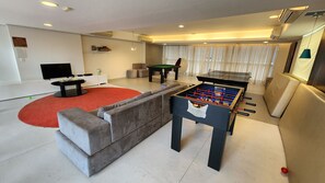 Un salon équipé d’un baby-foot, d’une table de billard, d’un canapé et d’un téléviseur.