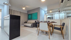 Uma sala de estar moderna com área de jantar, sofá, mesa de centro e televisão.