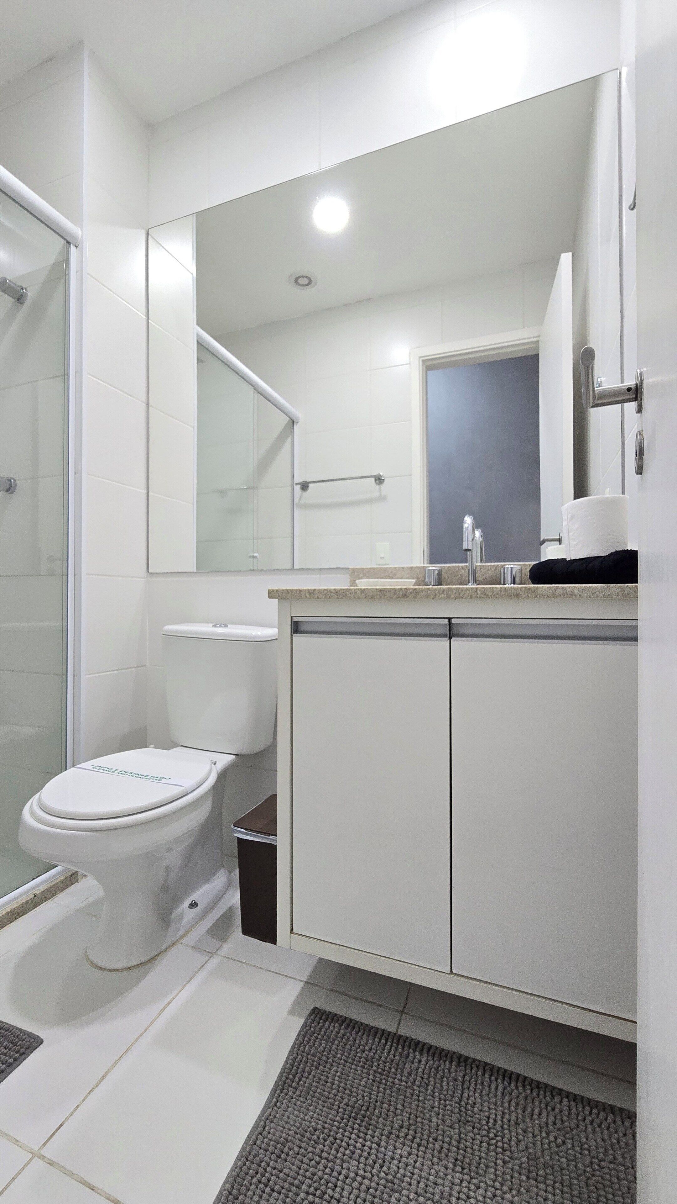 Uma casa de banho moderna com sanita, chuveiro e zona de lavatório.